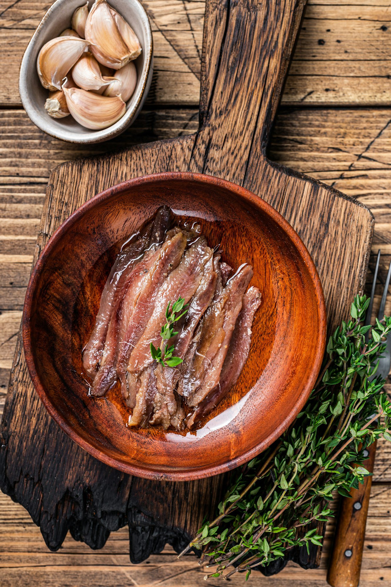 Canned Anchovies fish fillet in a wooden bowl. wooden background. Top view
