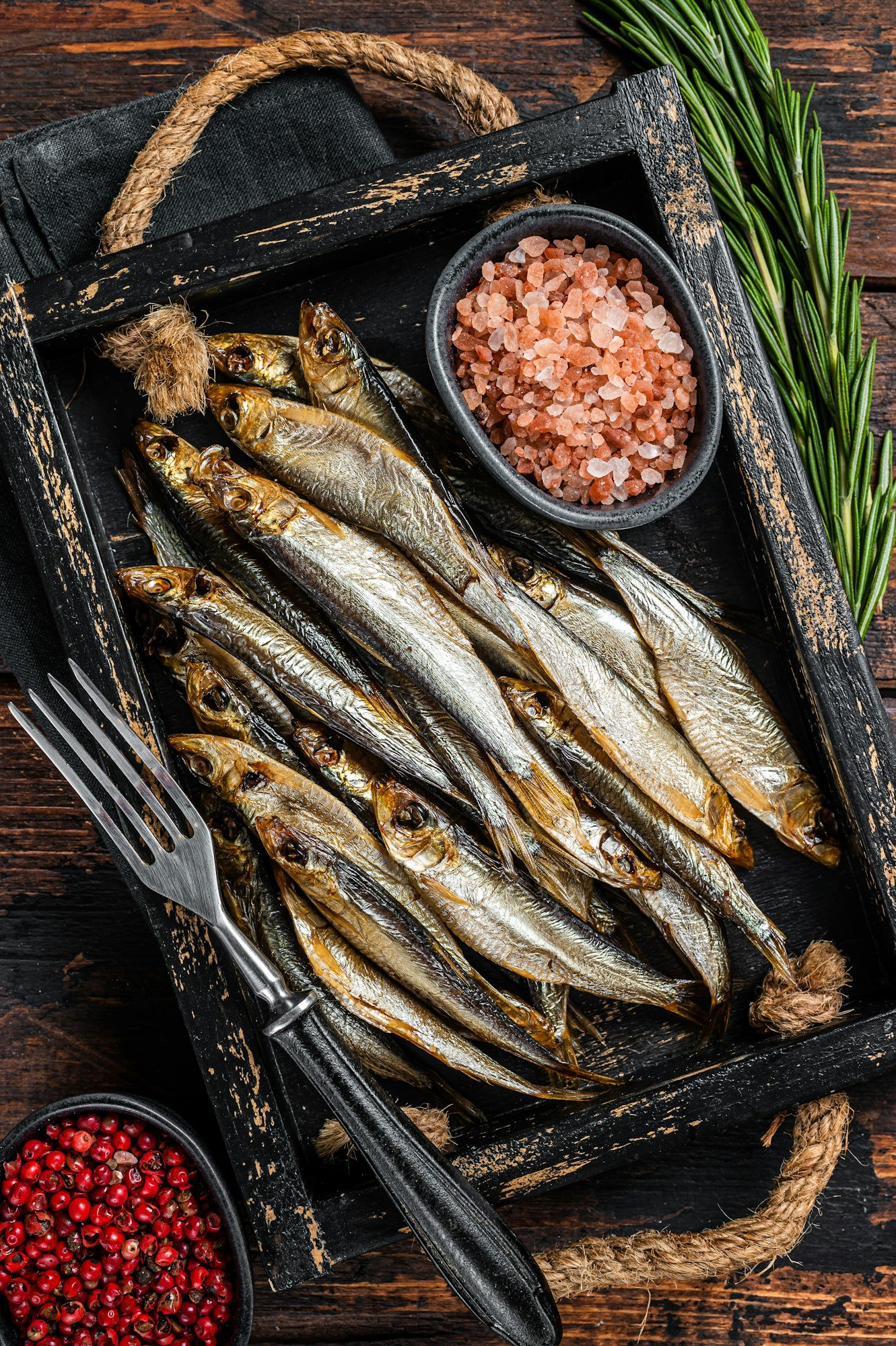 Fragrant Smoked sprat and Sardine fishes with herbs. Wooden background. Top view