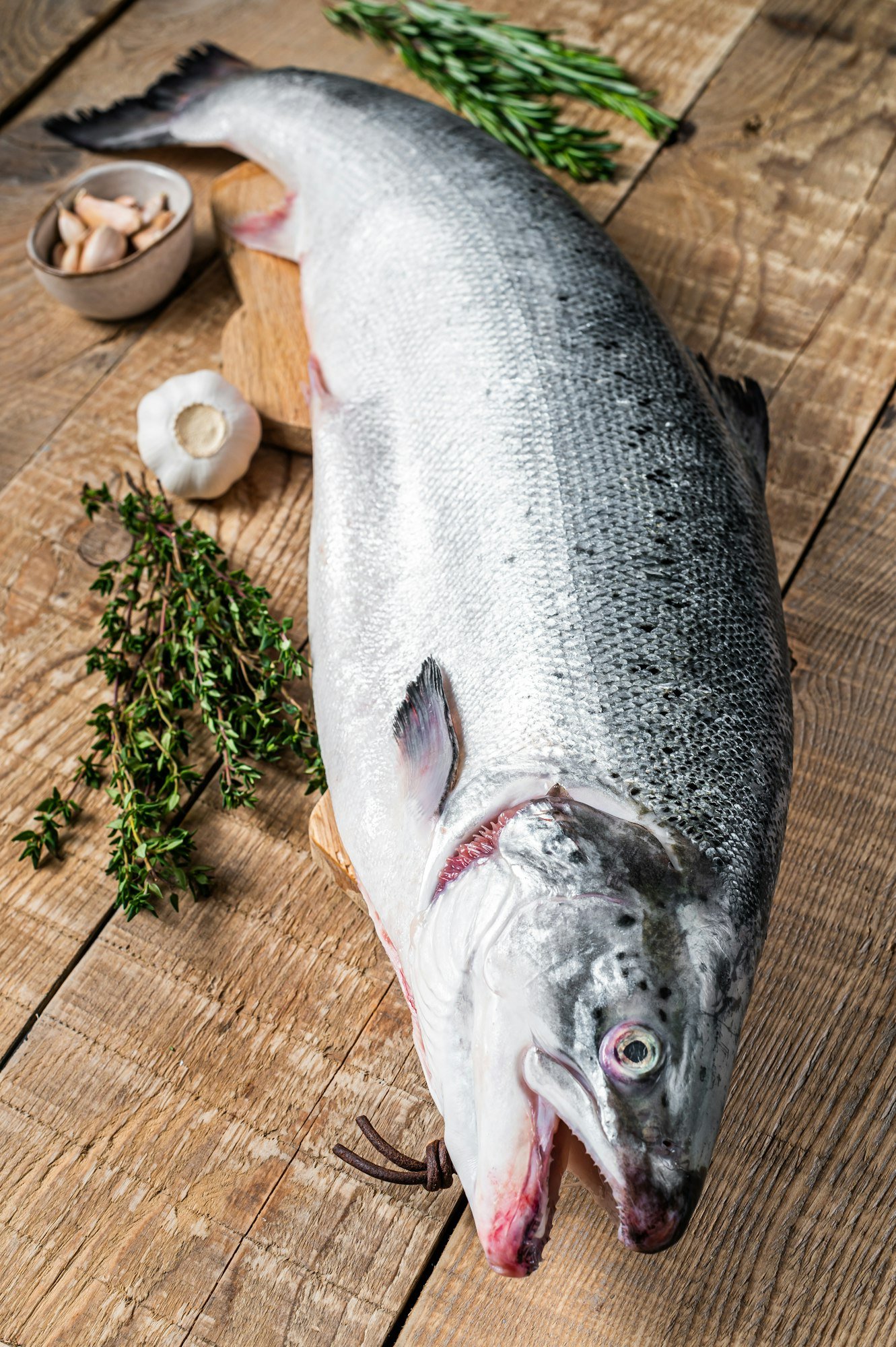Raw marine salmon fish on a wooden kichen table with herbs. Wooden background. Top view